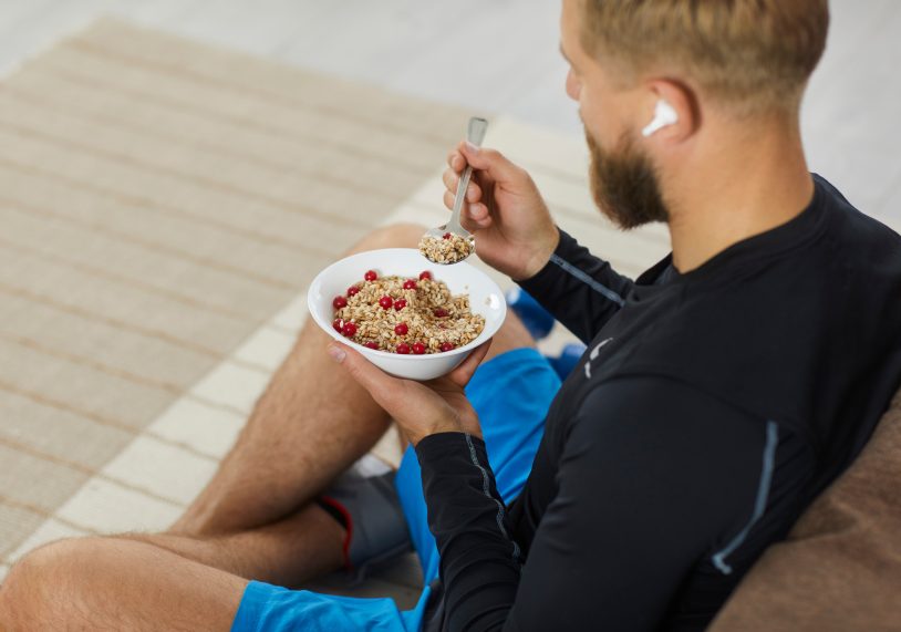 Young male athlete is having a bowl of healthy granola after his fitness workout